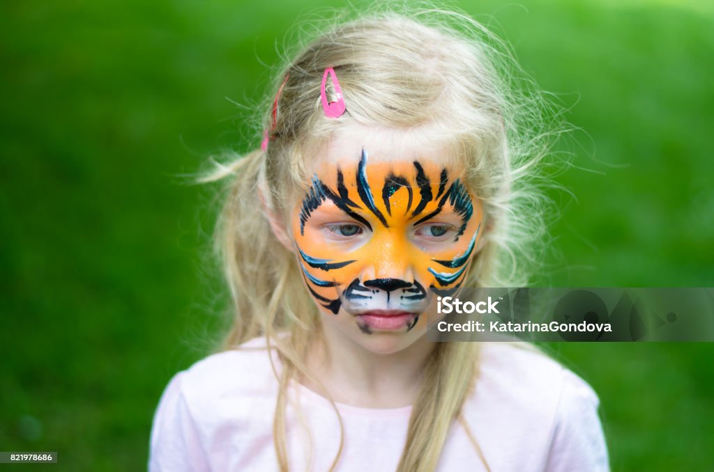 happy childhood little lovely blond girl with tiger face painting Beauty Stock Photo