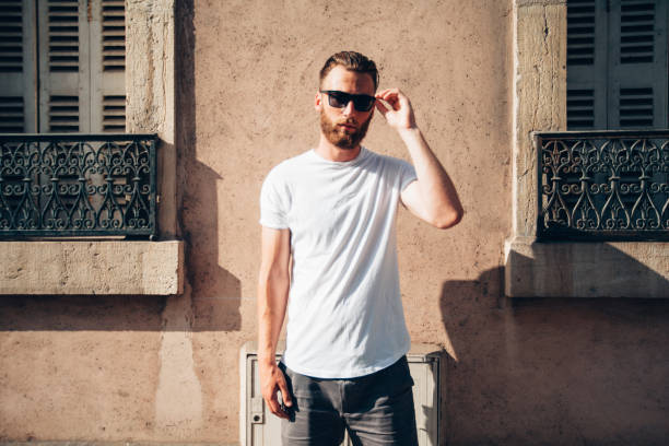 istock Hipster handsome male model with beard wearing white blank t-shirt with space for your logo or design in casual urban style 821993010