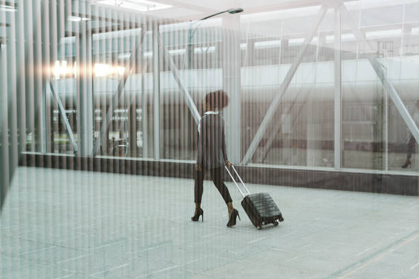 istock Modern businesswoman pulling her suitcase, back view shot through window 822002802