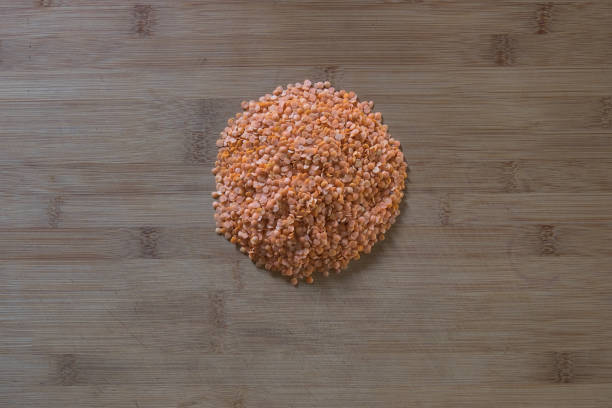 Red Lentils in a circular formation on wooden board stock photo