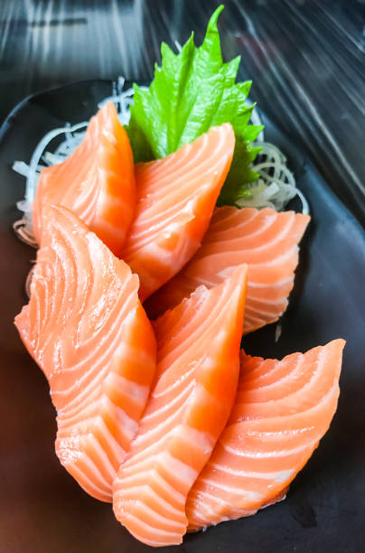 istock Japanese food: salmon sashimi (fresh raw salmon meat) decorated with grated turnip and mint leaf on wooden table as a background. 822023144