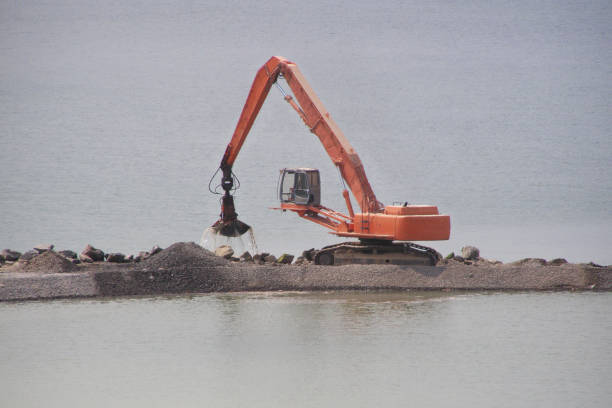 żuraw stoi na sztucznym wybrzeżu wylewa piasek na sztuczny brzeg rzeki. - industrial ship earth mover barge yellow zdjęcia i obrazy z banku zdjęć