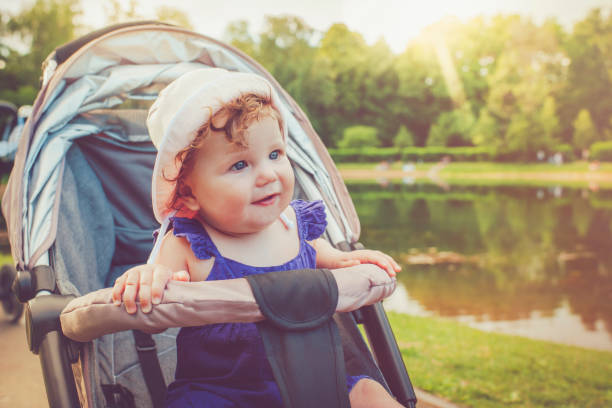 Happy baby girl sitting in stroller enjoying summer day