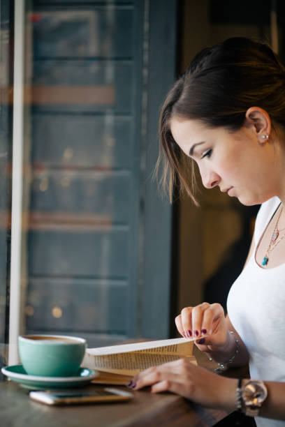 istock Girl Drinking Coffee and Reading Book in Cafe 822083596