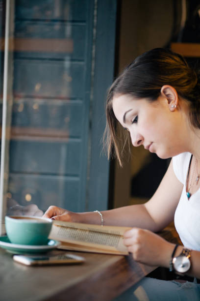 istock Girl Drinking Coffee and Reading Book in Cafe 822084844