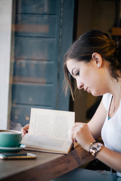 istock Girl Drinking Coffee and Reading Book in Cafe 822084852