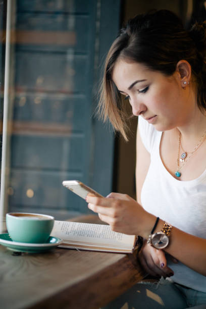 istock Girl Drinking Coffee and Reading Book in Cafe 822085364