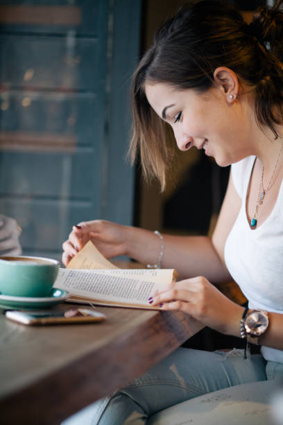 istock Girl Drinking Coffee and Reading Book in Cafe 822085616