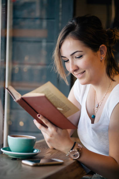 istock Girl Drinking Coffee and Reading Book in Cafe 822086504
