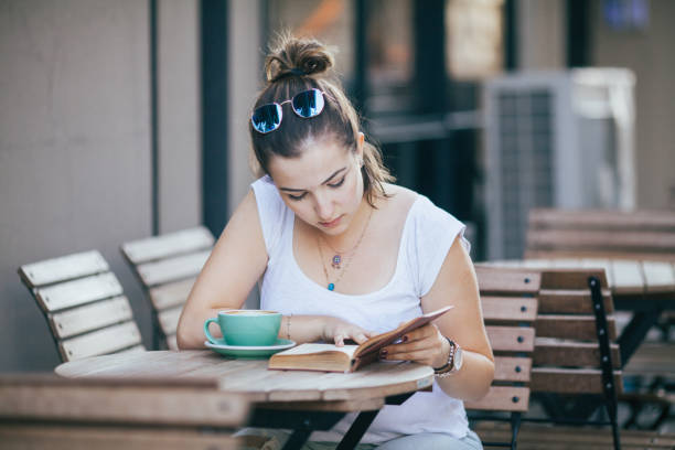 istock Girl Drinking Coffee and Reading Book in Cafe 822087680