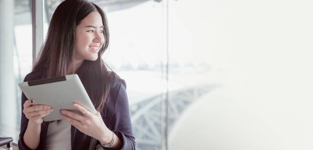 istock Young female passenger at the airport, using her tablet computer while waiting for her flight 822101298
