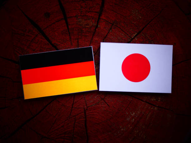 German flag with Japanese flag on a tree stump isolated stock photo