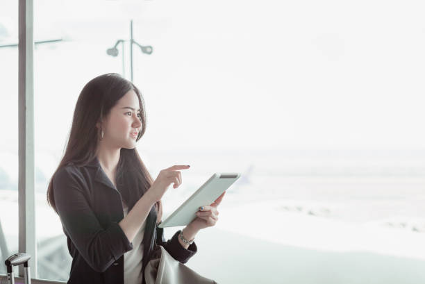 istock Young female passenger at the airport, using her tablet computer while waiting for her flight 822101372