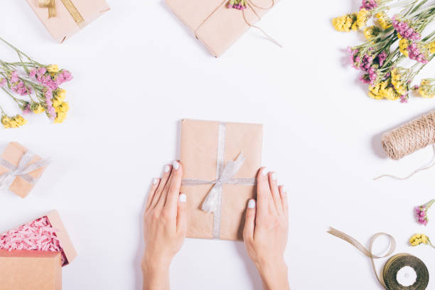 istock Female hands pack gifts and make decorations on a white table 822119650