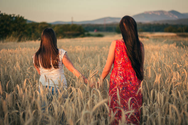istock Two beautiful young woman walking in a wheat field. 822123772