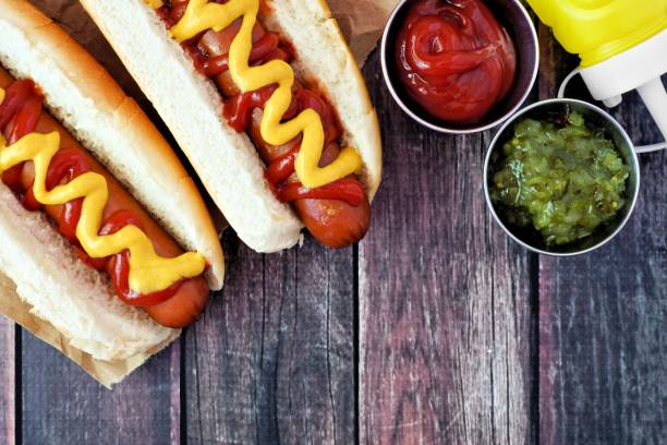 hot dogi z musztardą i ketchupem, scena nad głową na rustykalnym drewnie - relish zdjęcia i obrazy z banku zdjęć