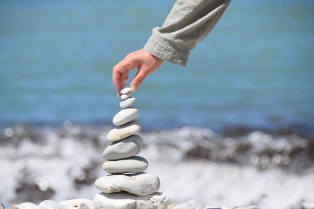 person macht stein turm am strand - nur hand - stone stability balance zen like stock-fotos und bilder