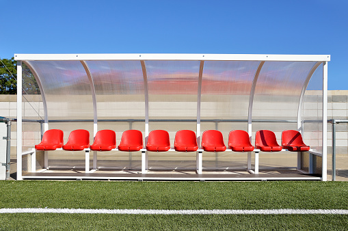 Banco y sillas de plástico rojo para los jugadores en el estadio photo