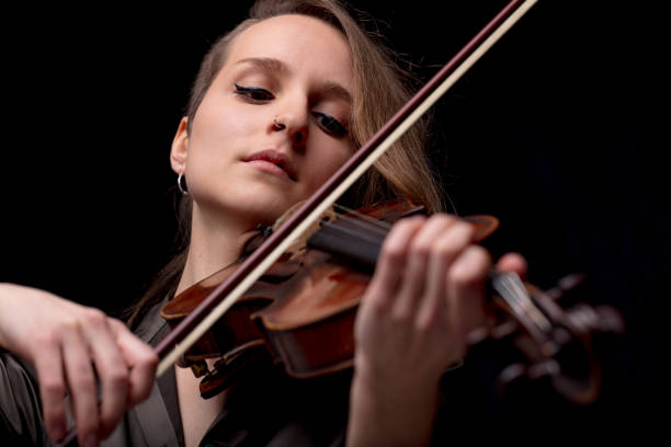 istock serious pretty woman playing violin on black 822173082