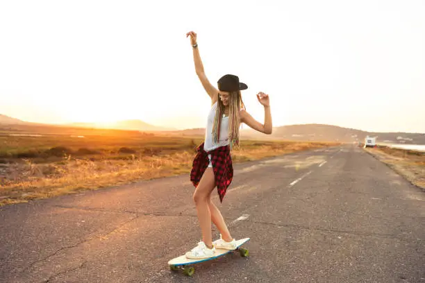 Beautiful young woman longboarding on road, moving down.