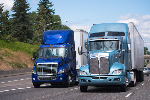 Dos grandes plataformas de camiones semi en tono azul y diferentes modelos con trailerd conducir de lado a lado photo