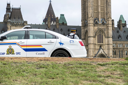 RCMP car in front of the Canada Parliament, Ottawa. This image shows a Royal Canadian Mounted Police vehicle and a Police Officer on display.
