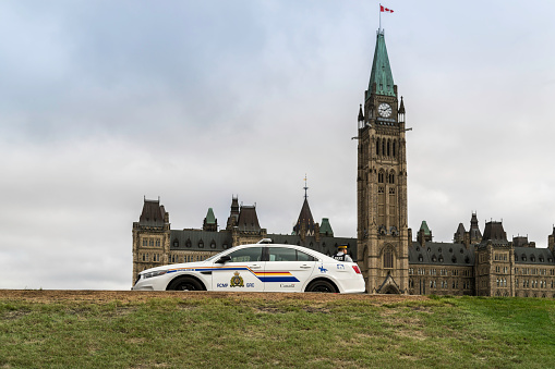 RCMP car in front of the Canada Parliament, Ottawa. This image shows a Royal Canadian Mounted Police vehicle and a Police Officer on display.
