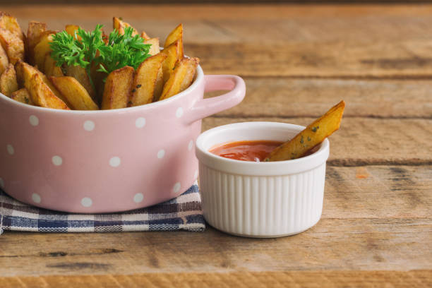 homemade french fries serve with ketchup and sour cream or mayonnaise. golden brown crispy french fries sprinkle with salt and oregano in pink bowl for snack or appetizer. french fries on wood table. - oregano freshness herb brown imagens e fotografias de stock