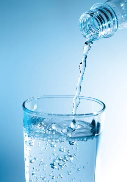 istock Pouring water from bottle into glass with blue light 822293438