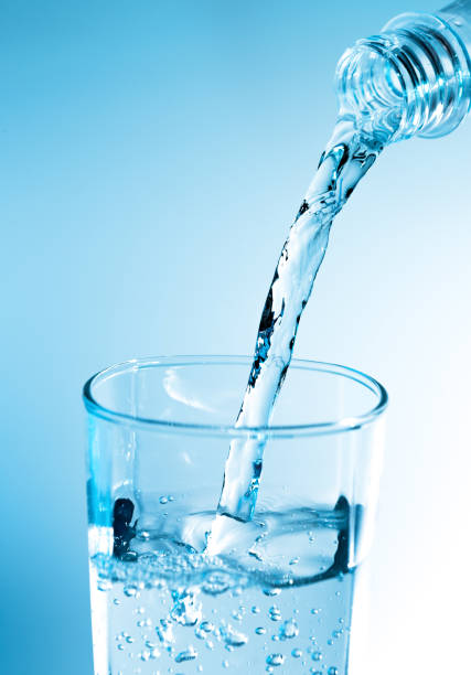 istock Pouring water from bottle into glass with blue light 822293454