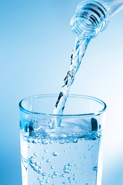 istock Pouring water from bottle into glass with blue light 822293460