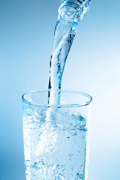 istock Pouring water from bottle into glass with blue light 822293466