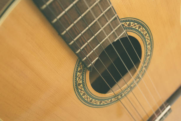 Old acoustic guitar hanging on nail on wooden wall, rustic music and vintage lifestyle concept