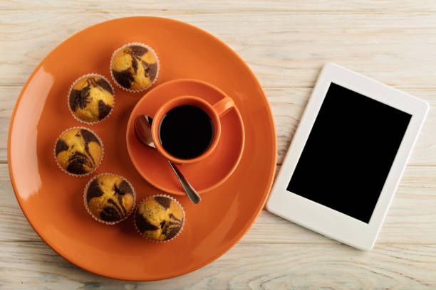 caffè con latte, muffin ed e-book. - coffee muffin pastry blueberry muffin foto e immagini stock