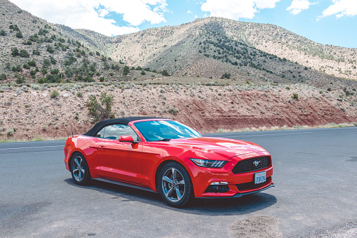 Grand Canyon Village, Arizona, USA - June 20, 2017: Red cabriolet car Ford Mustang in Crand Kenyon Village, Grand Canyon National Park, Arizona, USA. A trip to the US National Parks by car. Tourist attractions in the USA