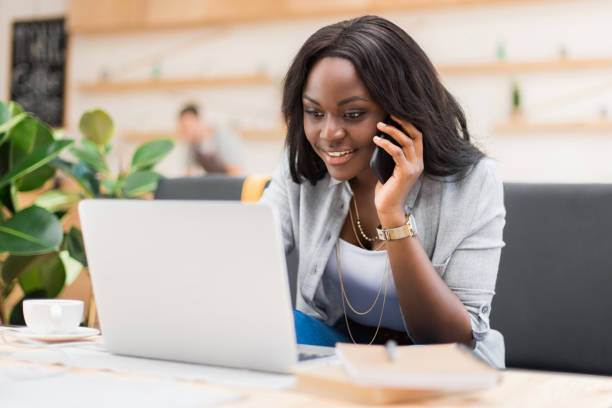 istock attractive african american woman talking on smartphone while using laptop in cafe 822362292