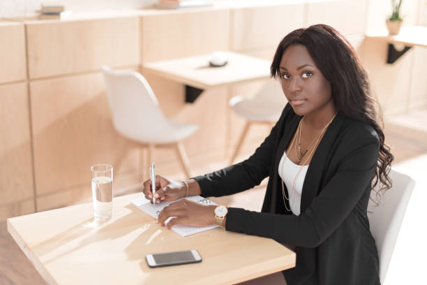istock beautiful african american woman writing in notepad while sitting in cafe 822365948