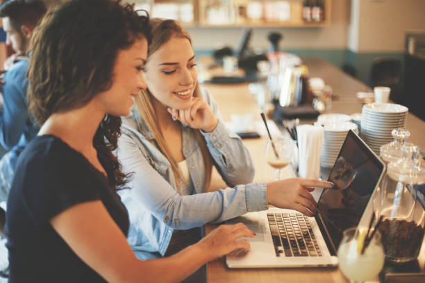 istock Happy girls using laptop in cafe 822381034