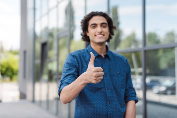 istock handsome young man showing thumb up and smiling at camera 822387528