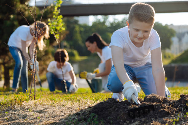 istock Positive delighted blonde boy raking ground 822398450