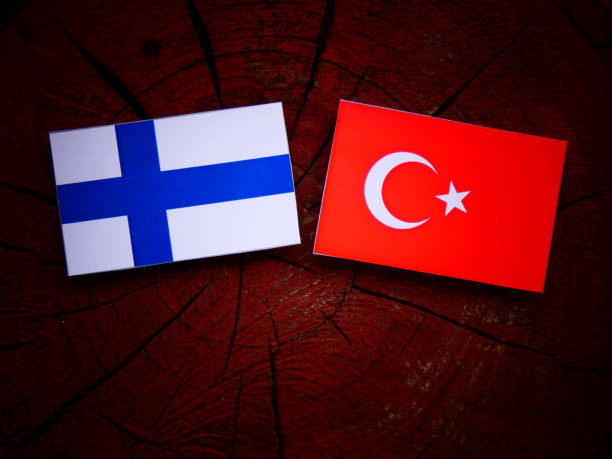 Finnish flag with Turkish flag on a tree stump isolated stock photo