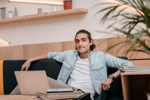istock handsome young small business owner using laptop and smiling at camera 822418024