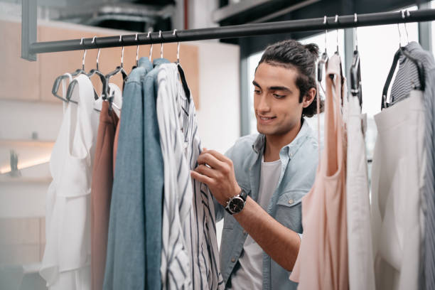 istock handsome smiling young man working with clothes in boutique 822433412