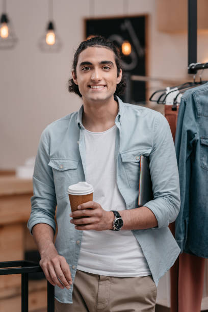 istock handsome young man drinking coffee from paper cup and smiling at camera 822433610