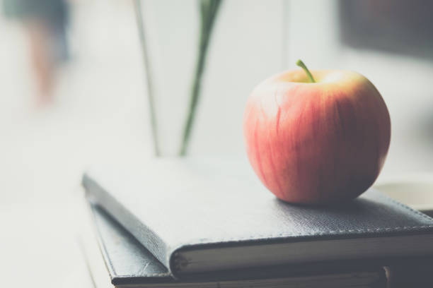 Apples placed on books and notebooks in the morning light.The image is blurred and Soft focus. stock photo