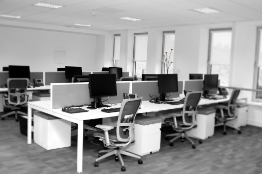 Black and white shot of an empty office with colour accents in the background and a blurred vignette.