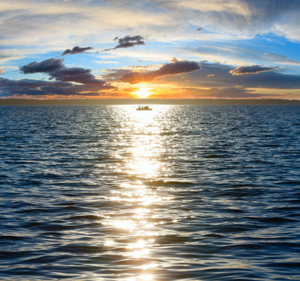 istock Sun track and fishing boat on lake surface. 822475320