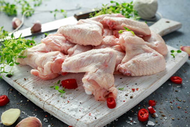 istock Fresh raw chicken wings on a white cutting board with thyme, chilli, salt, pepper, garlic 822524082