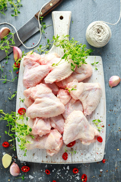 istock Fresh raw chicken wings on a white cutting board with thyme, chilli, salt, pepper, garlic 822524302