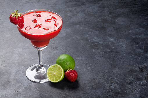 Strawberry margarita cocktail on dark stone table. With copy space
